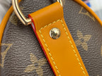 Louis Vuitton monogram bag detail with orange leather tab and round gold emblem