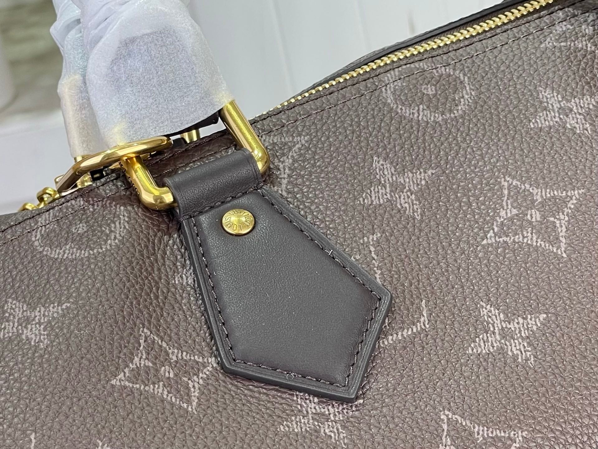 Louis Vuitton monogram bag corner with gold-tone hardware and leather luggage tag