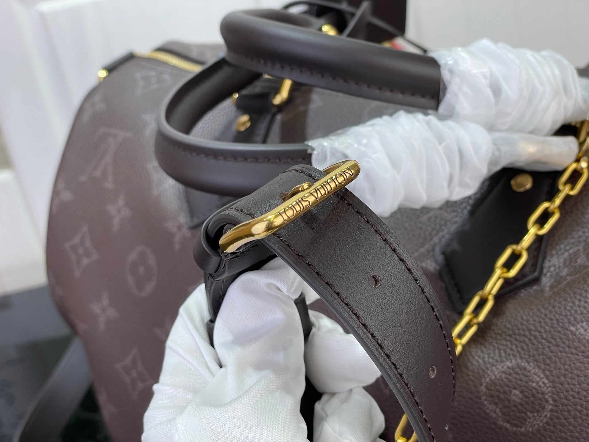 Louis Vuitton bag strap and gold chain detail in dark monogram leather