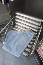 Light blue denim pants folded on metal rack with patch pockets