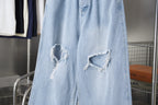 Light blue denim pants with two distressed knee rips and frayed cuffs