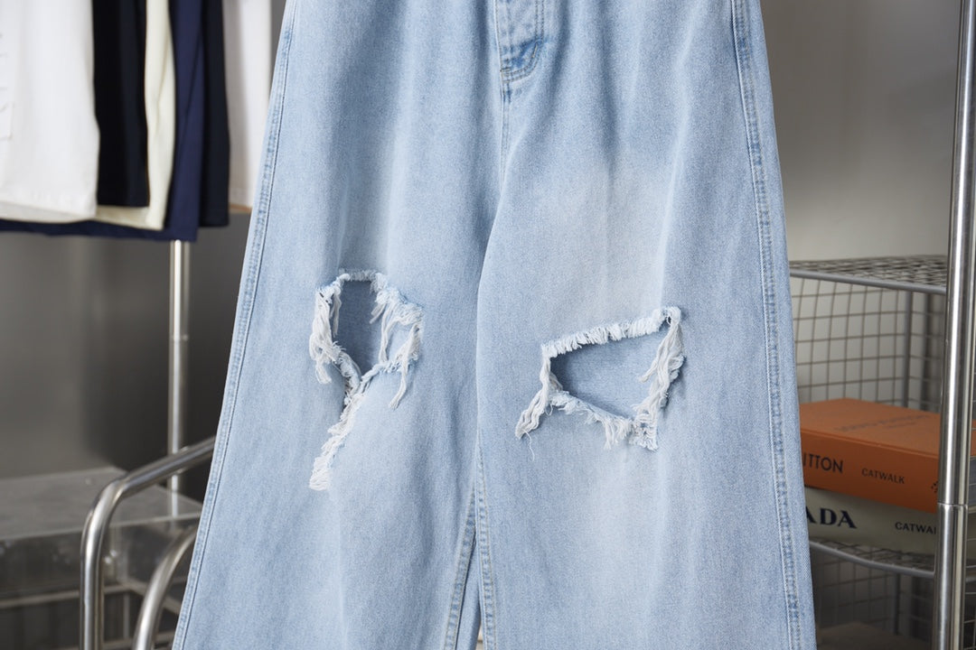 Light blue denim pants with two distressed knee rips and frayed cuffs