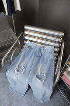 Light blue denim pants folded on metal rack, distressed knees