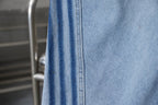 Light blue denim fabric with stitched panel seams and vertical pocket edge