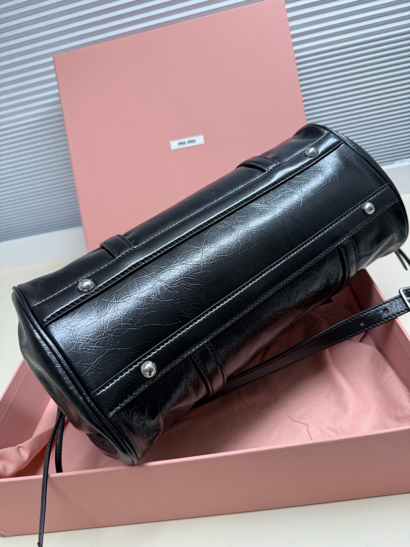 Black leather shoulder bag with long front flap, snap buttons, and crossbody strap