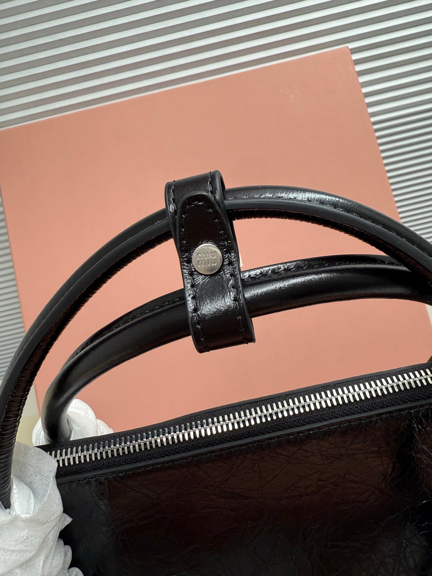 Black leather handbag top zipper with strap loop and wide leather handle