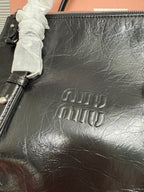Black leather tote with embossed Miu Miu logo and textured grain finish