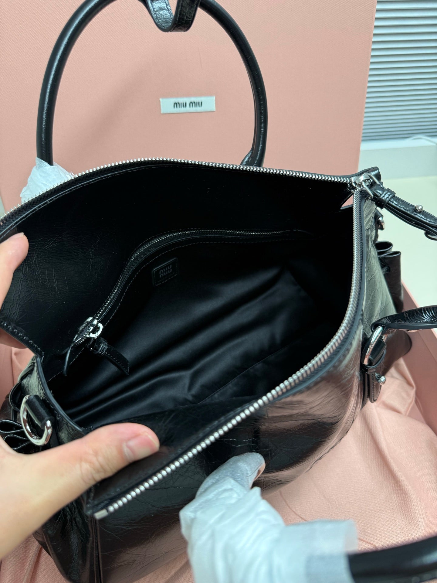 Black leather handbag interior view with zipper top and shoulder strap
