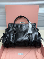 Black leather handbag with top handle, side rings, and front seam detail