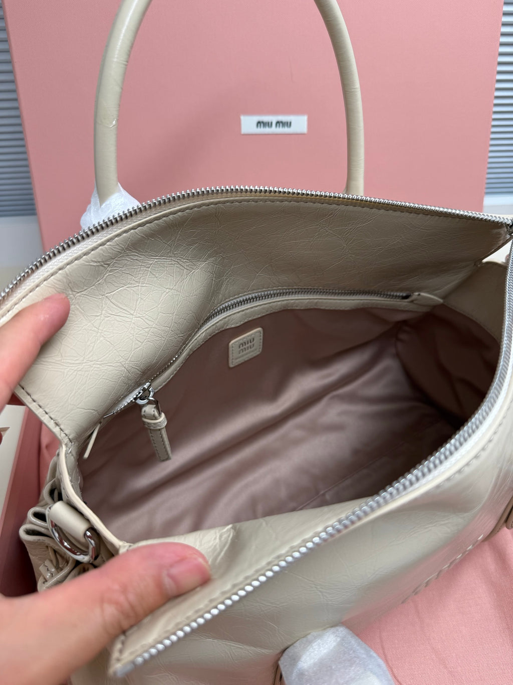 Ivory leather handbag open top with logo patch and interior lining view