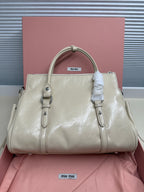 Ivory leather handbag with double top handles, front buckled tabs, and logo patch
