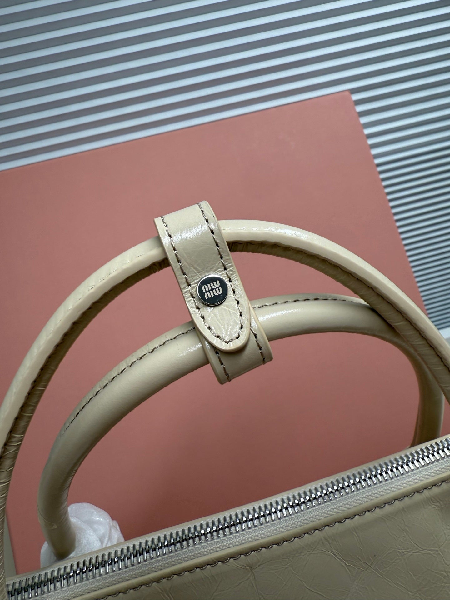 Ivory leather handbag handle with logo patch and stitched leather strap detail