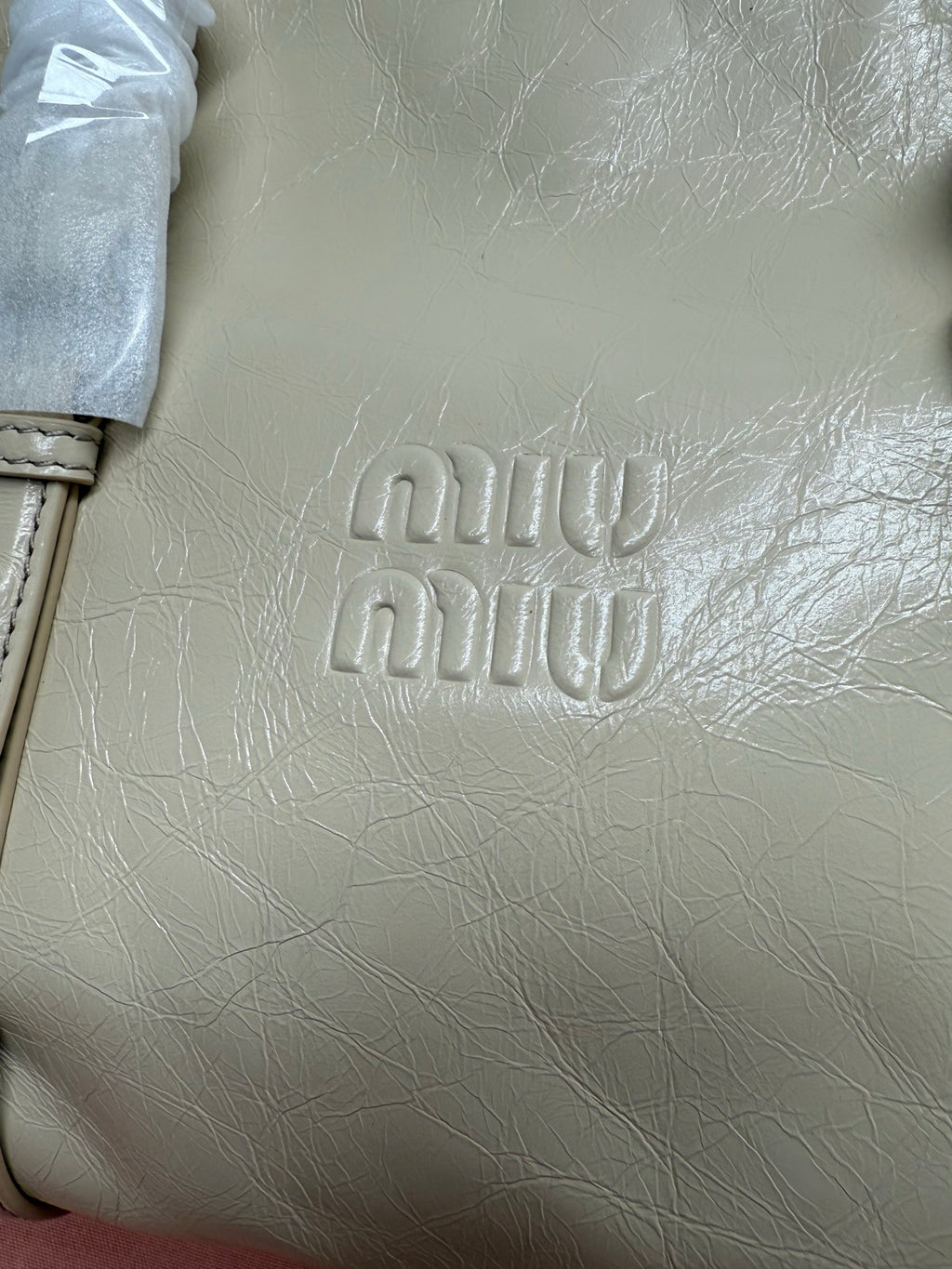 Ivory leather handbag front with embossed “miu miu” logo detail