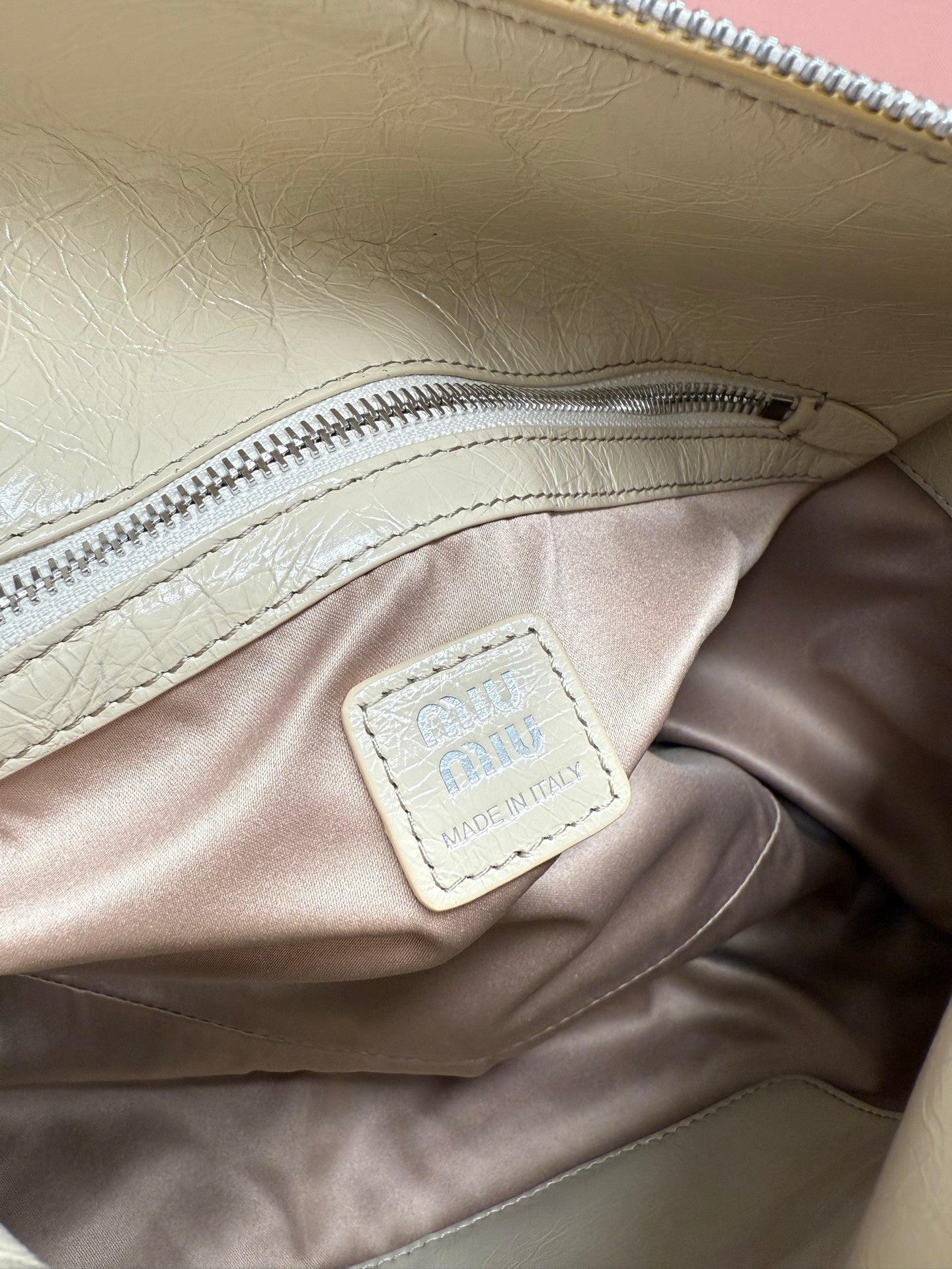 Ivory leather handbag interior pocket with “miu miu” stitched label
