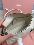 White leather handbag open view with zip top, fabric lining, and inner pocket