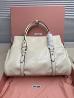 White leather handbag tote with top handles, front zip, miu miu label, side buckle details