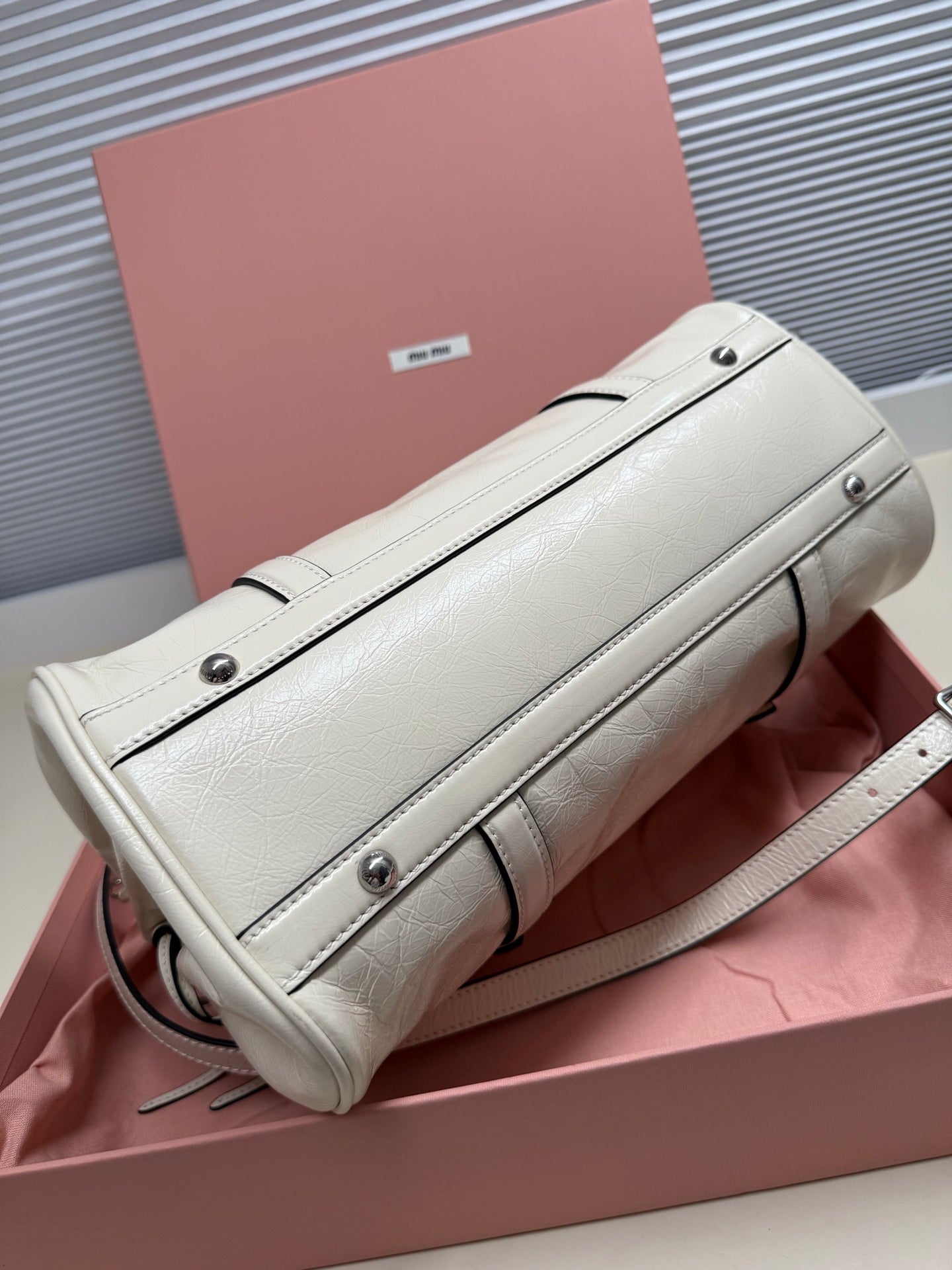 White leather shoulder bag with flap trim, silver-tone hardware, and detachable strap