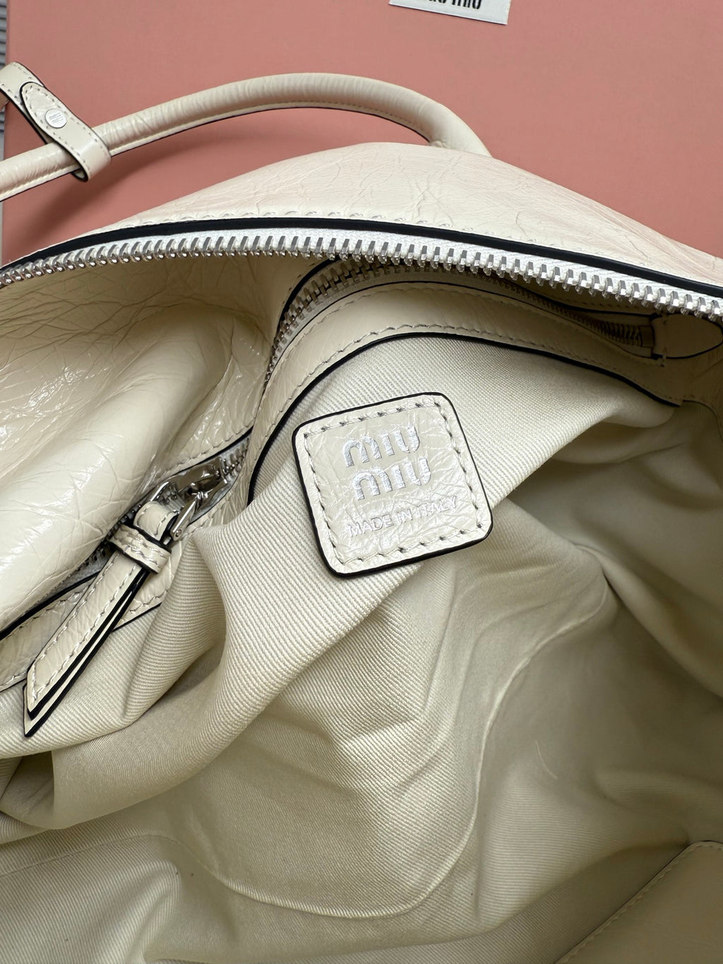 White leather handbag interior view with zip opening and small miu miu logo patch