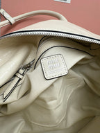 White leather handbag interior view with zip opening and small miu miu logo patch