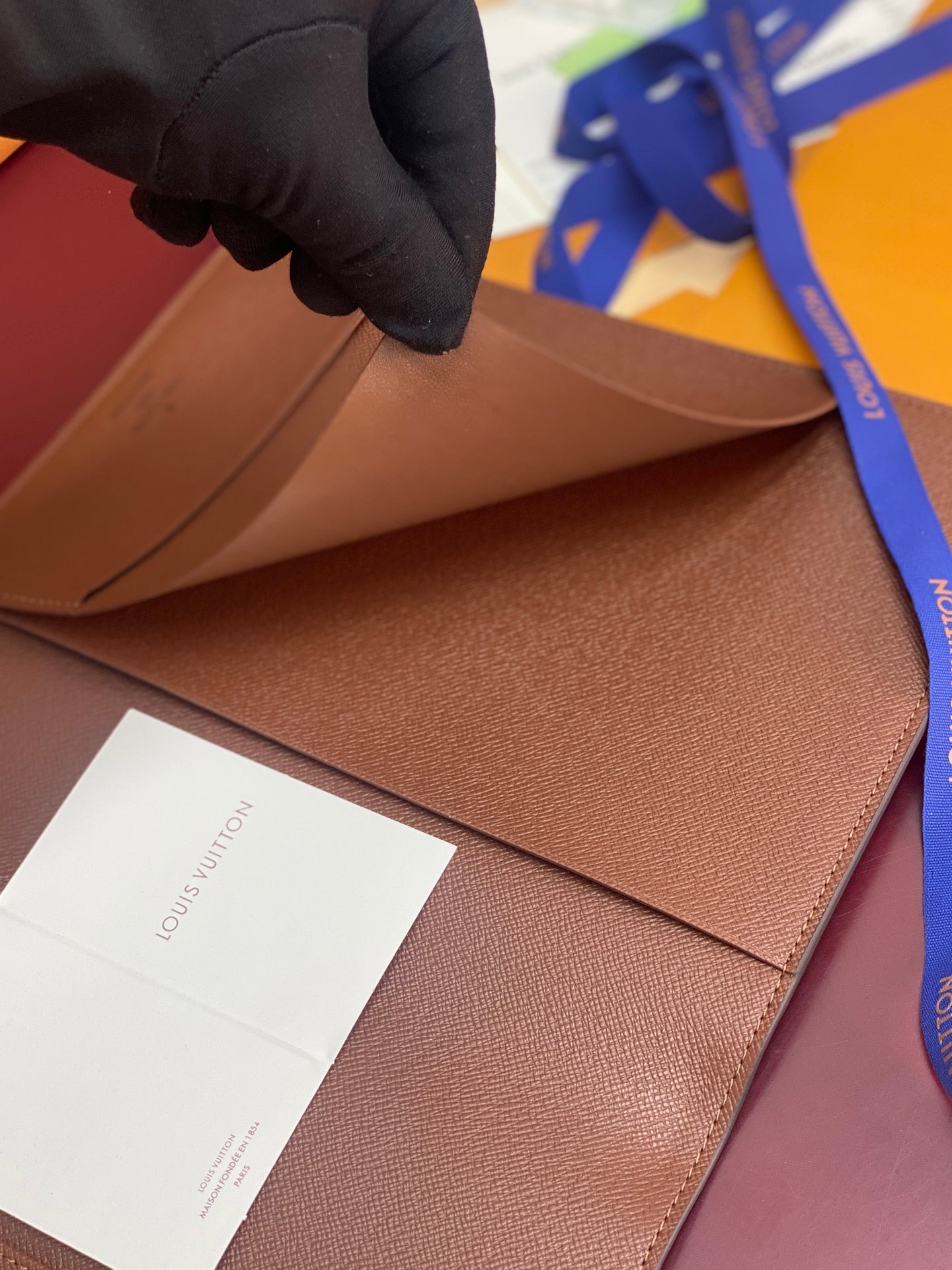 Louis Vuitton small brown leather card wallet being handled, interior slot visible