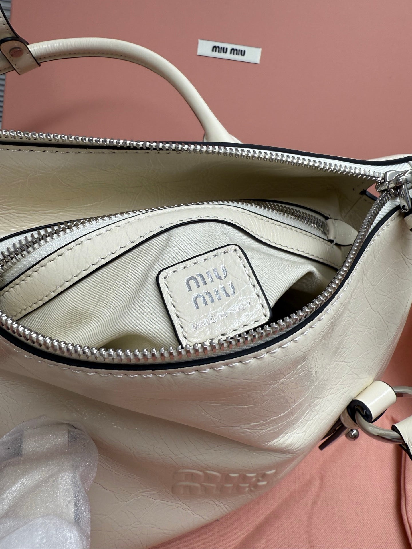White leather bag interior with zip pocket and small miu miu logo patch