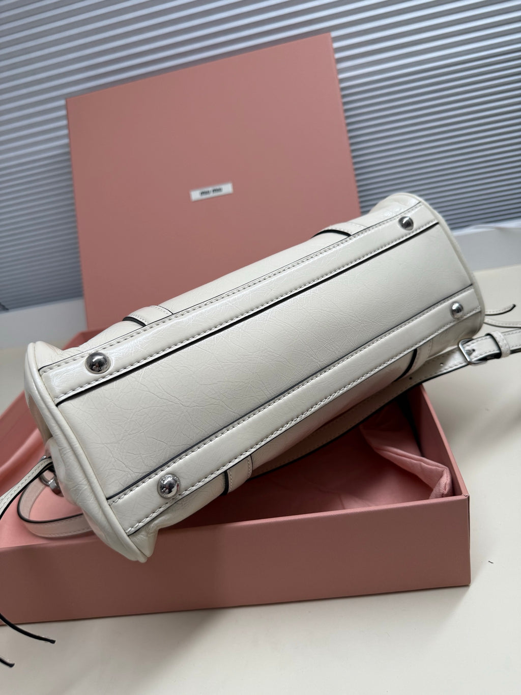 White leather mini shoulder bag with top zipper, flap, and metal snap closures