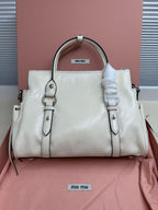 White leather mini tote bag with two front rings, top handles, and attached straps