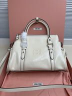 White leather mini tote bag with top handles, front logo, and side straps