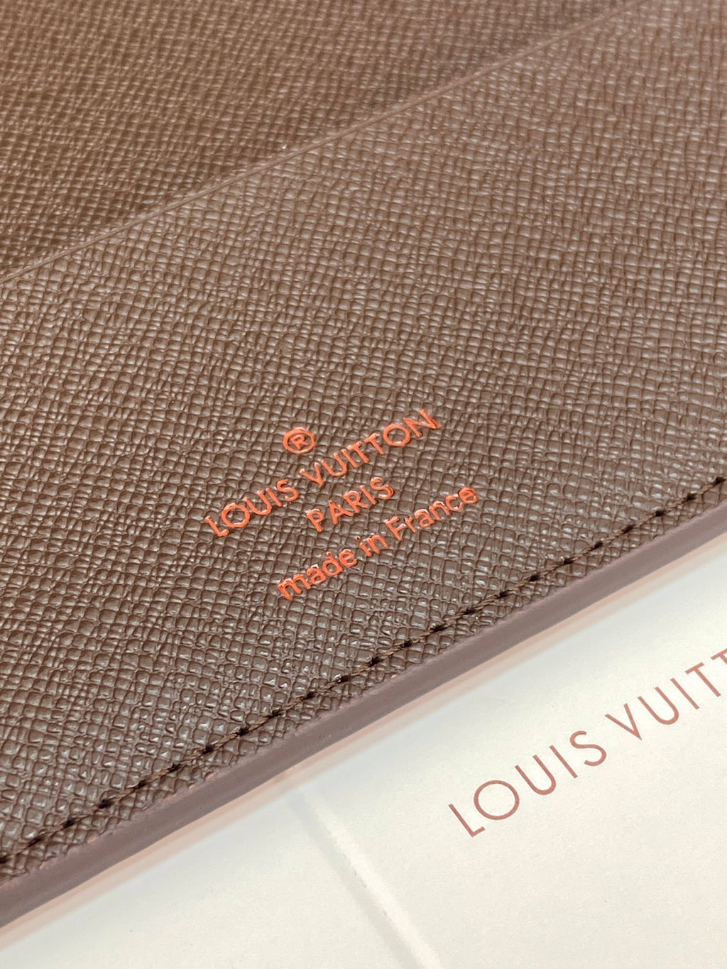 Louis Vuitton embossed logo and stitching detail on textured wallet