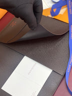 Louis Vuitton small wallet in dark textured leather, shown with glove holding corner