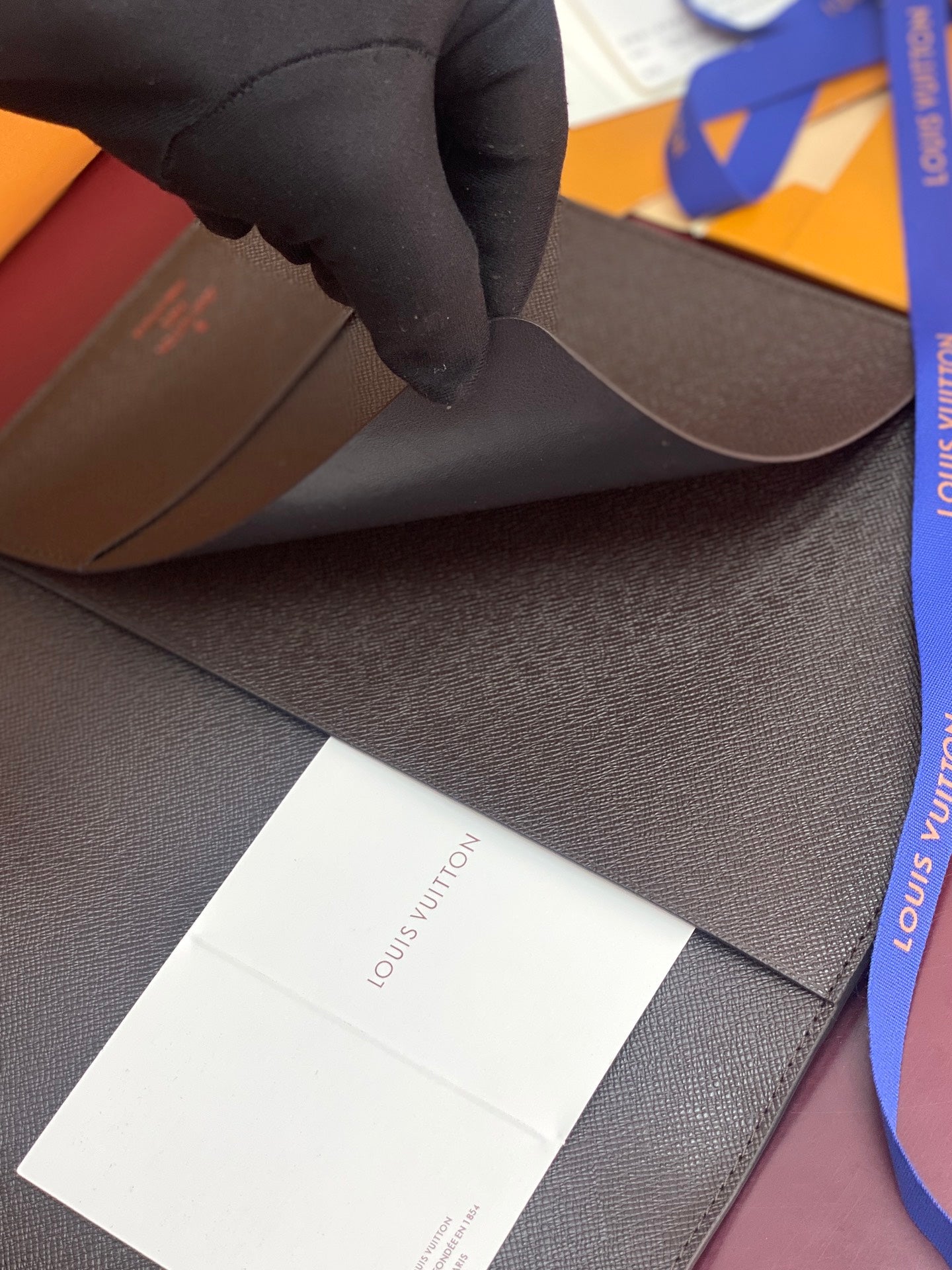 Louis Vuitton dark wallet exterior with paper insert and ribbon