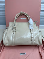 Light green leather tote handbag with zip closure, dual handles, side rings and logo tag