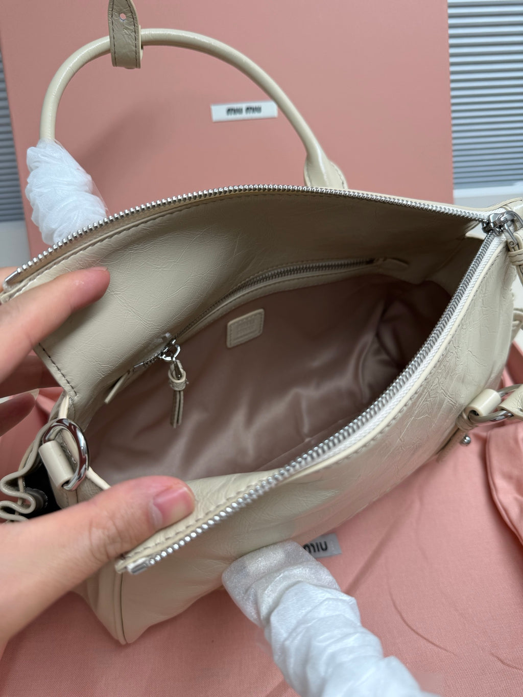 Light green leather handbag open top showing interior and zip pocket