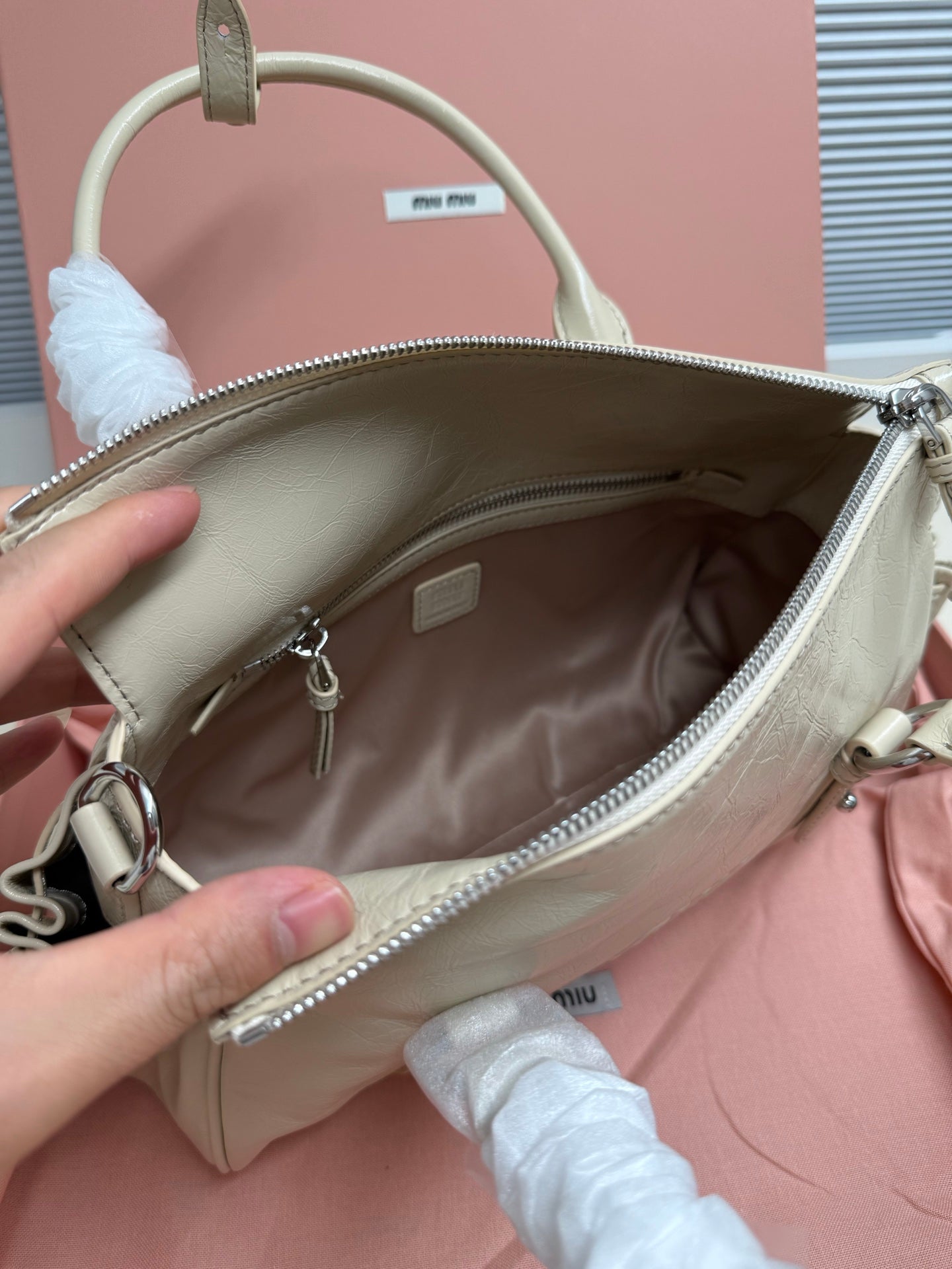 Light green leather handbag open top showing interior and zip pocket
