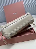 Light green leather handbag with rear flap pocket, metal snaps, and shoulder strap