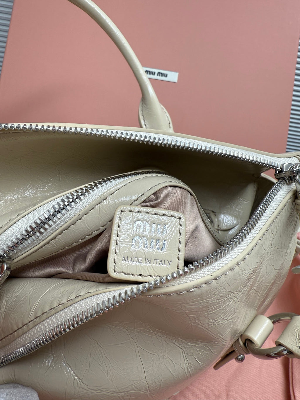 Light green leather handbag interior with zip pocket and 'Made in Italy' patch
