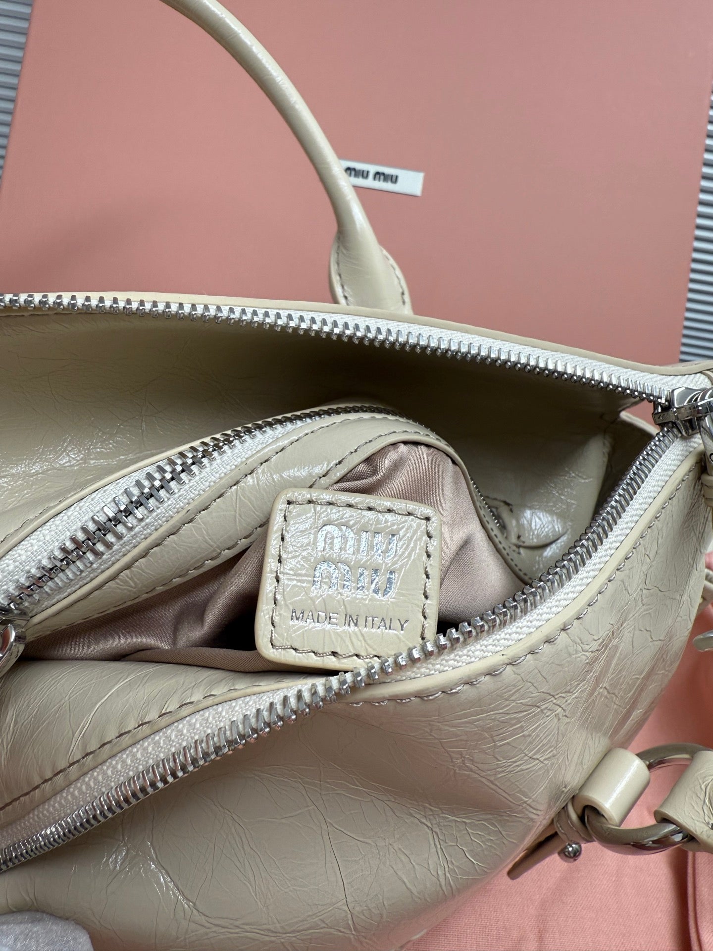 Light green leather handbag interior with zip pocket and 'Made in Italy' patch