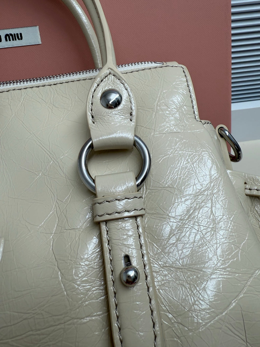 Light green leather handbag handle with metal ring and stitched strap detail