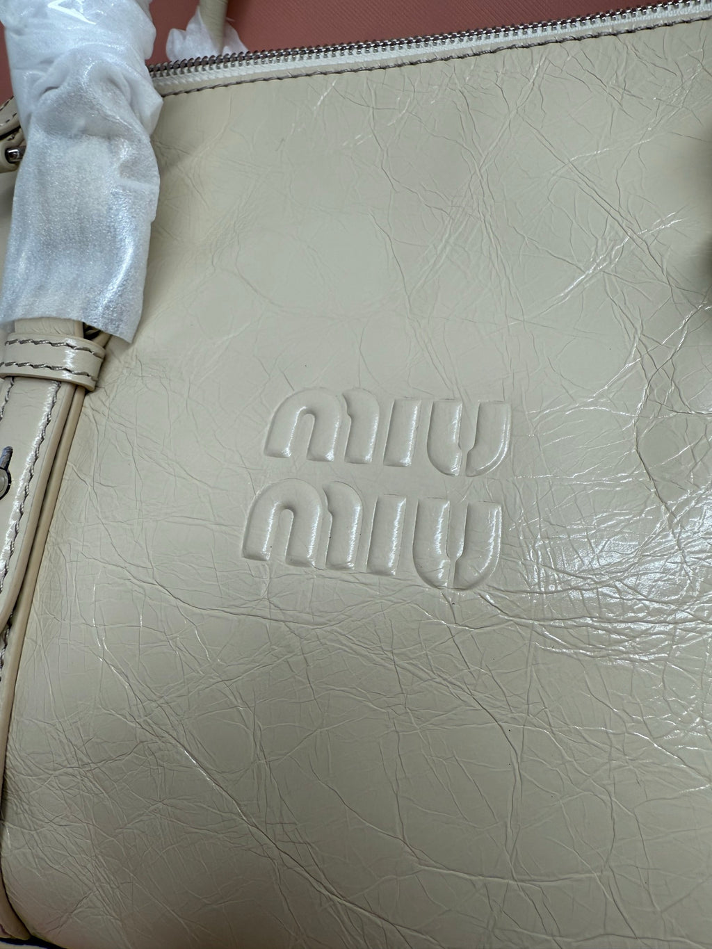 Embossed Miu Miu logo on light green leather handbag front panel