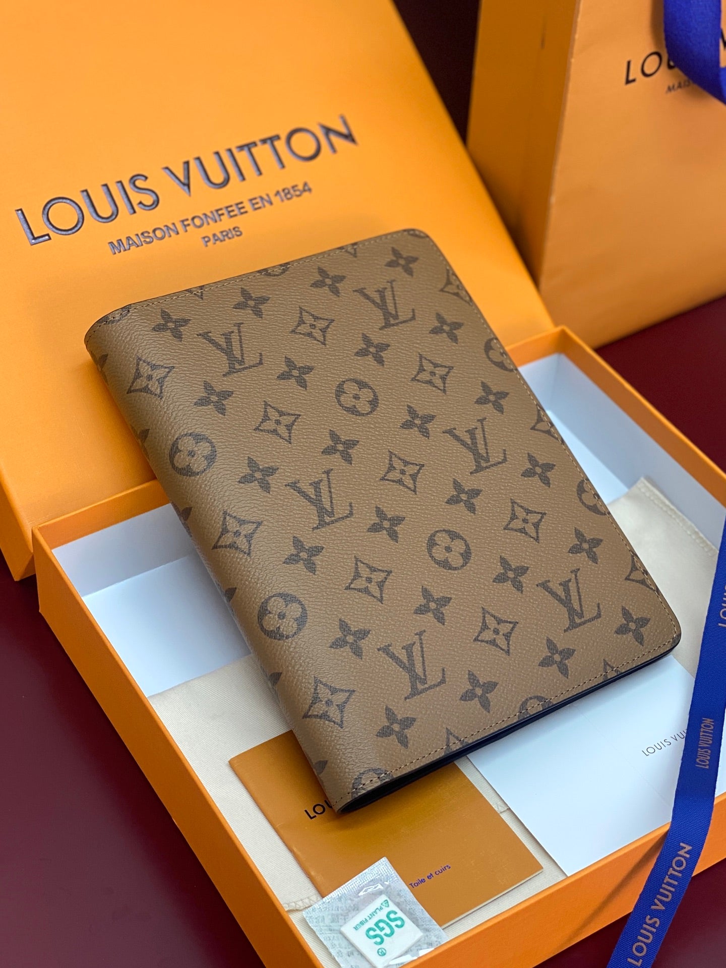 Louis Vuitton small bag in tan monogram canvas with slim profile and dark trim.