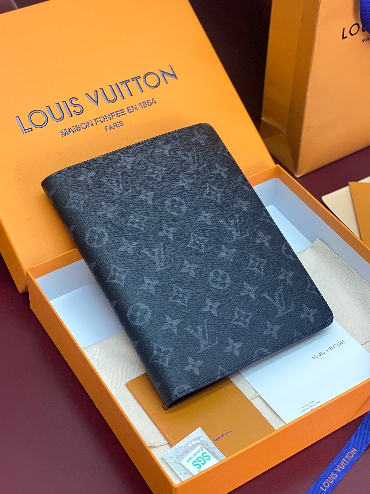 Louis Vuitton small bag with dark monogram canvas and foldover flap, corner visible