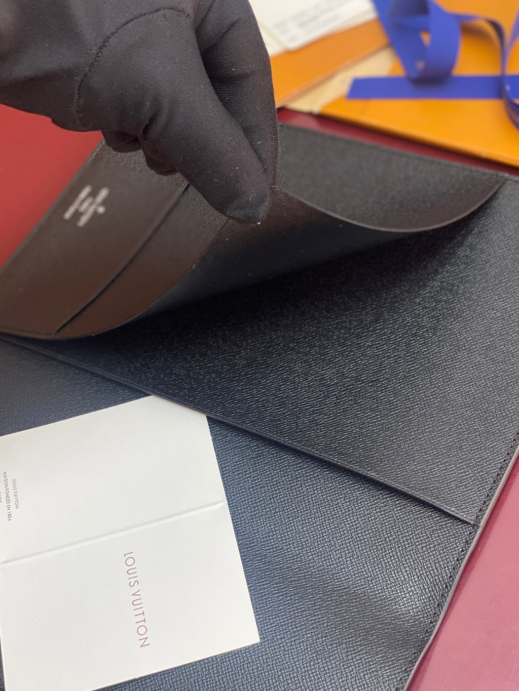 Louis Vuitton small wallet held open, textured dark exterior and card panel visible