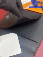 Louis Vuitton small wallet held open, textured dark exterior and card panel visible