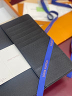 Louis Vuitton small bag in dark textured leather with layered front panel and navy ribbon.