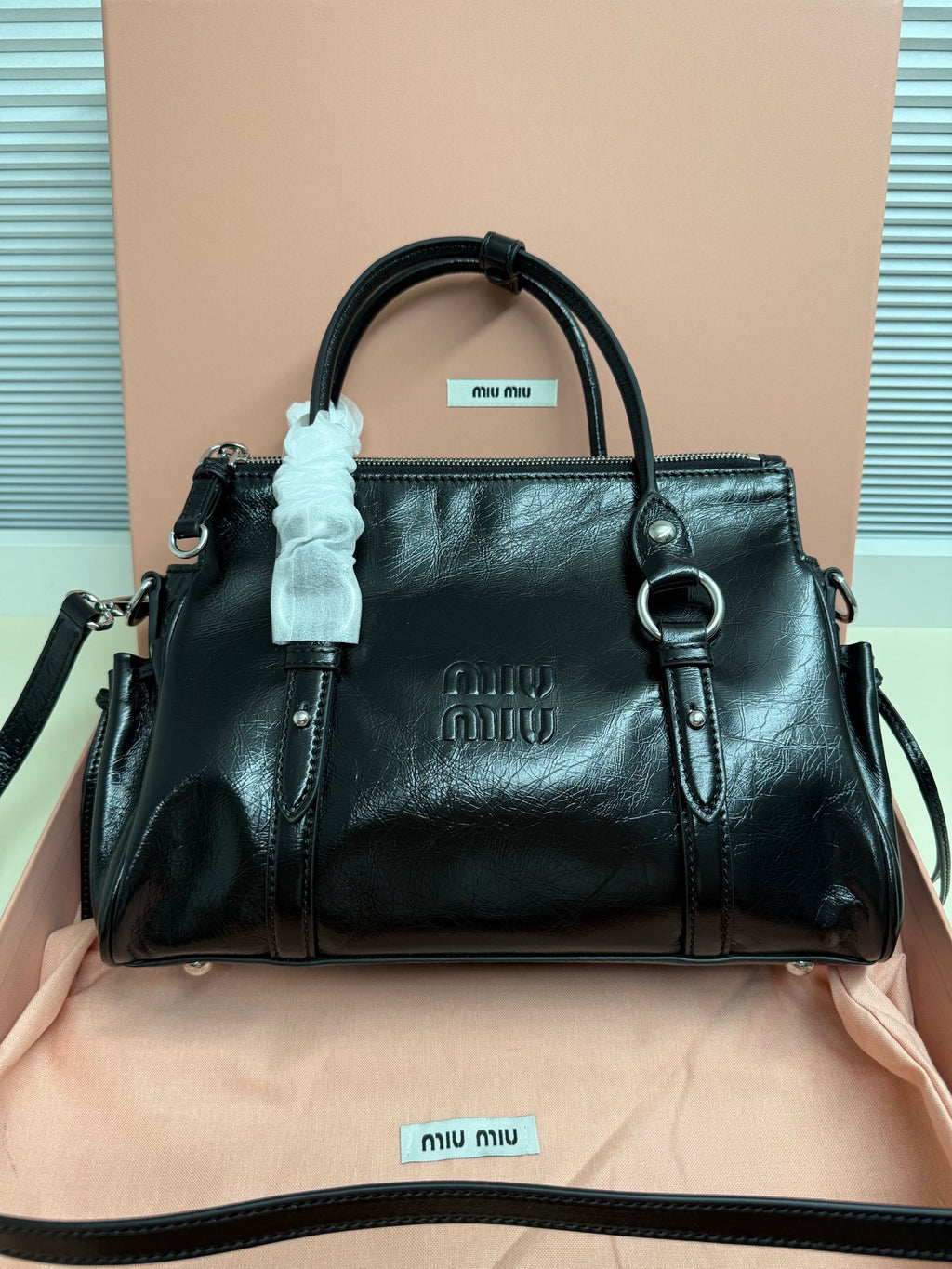 Dark leather handbag with top handles, front logo, zip closure.
