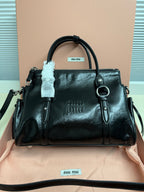 Dark leather handbag with top handles, front logo, zip closure.