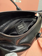 Dark leather handbag interior pocket with 'miu miu' logo patch and zip trim.