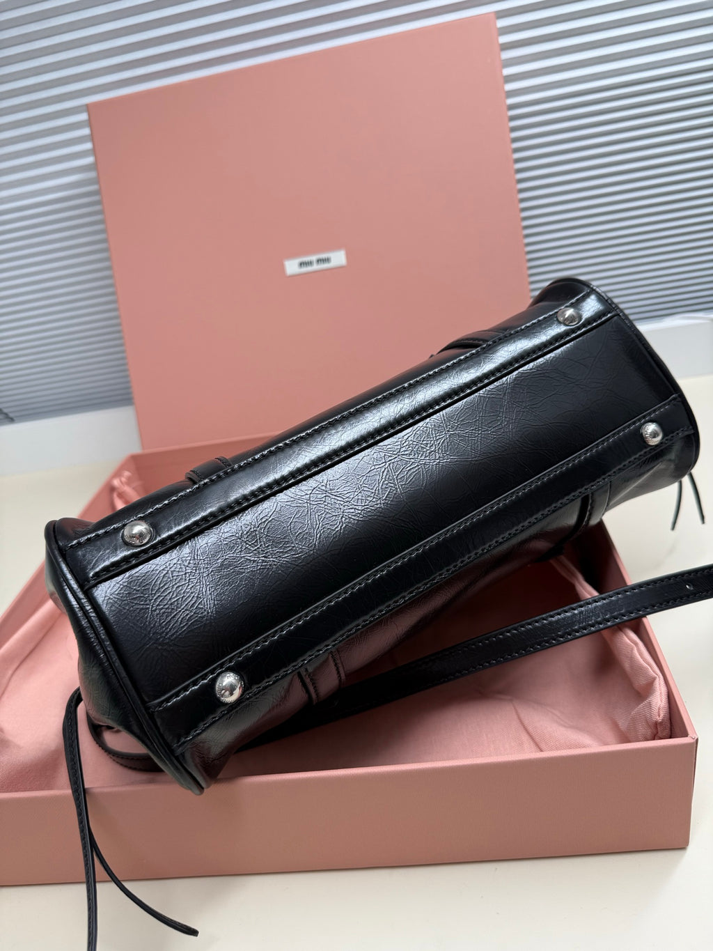 Black leather zip pouch clutch with metal studs and long shoulder strap.
