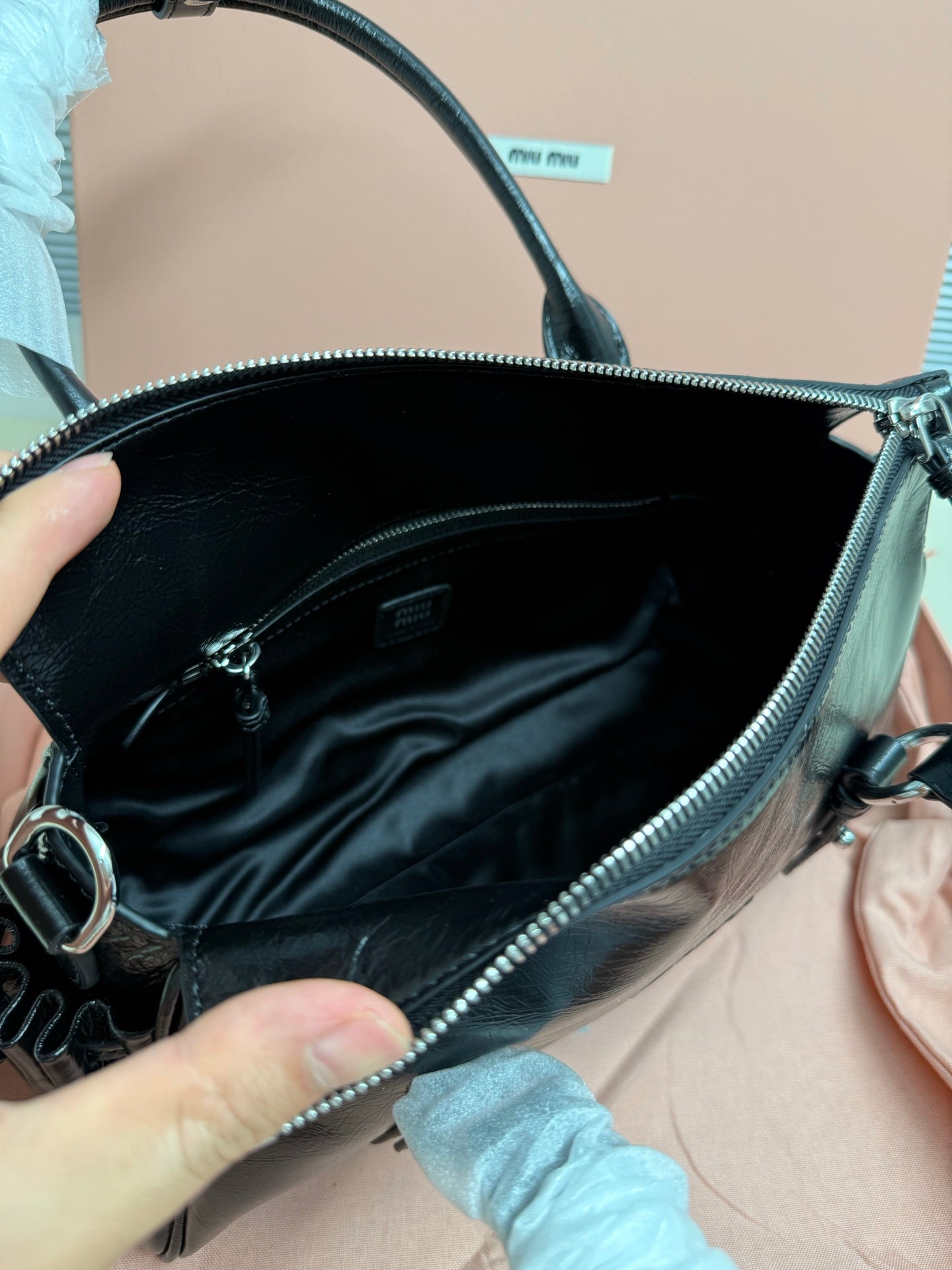 Dark leather mini handbag interior with lining and silver-tone zipper trim.