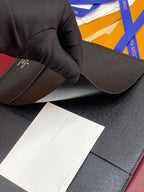 Dark textured leather wallet with card slot, held in gloved hand